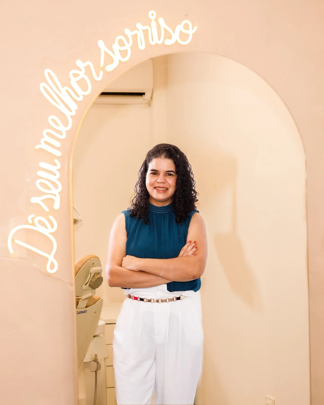 Dra. Maéli Barros sob o arco com o neon Dê o seu melhor sorriso
